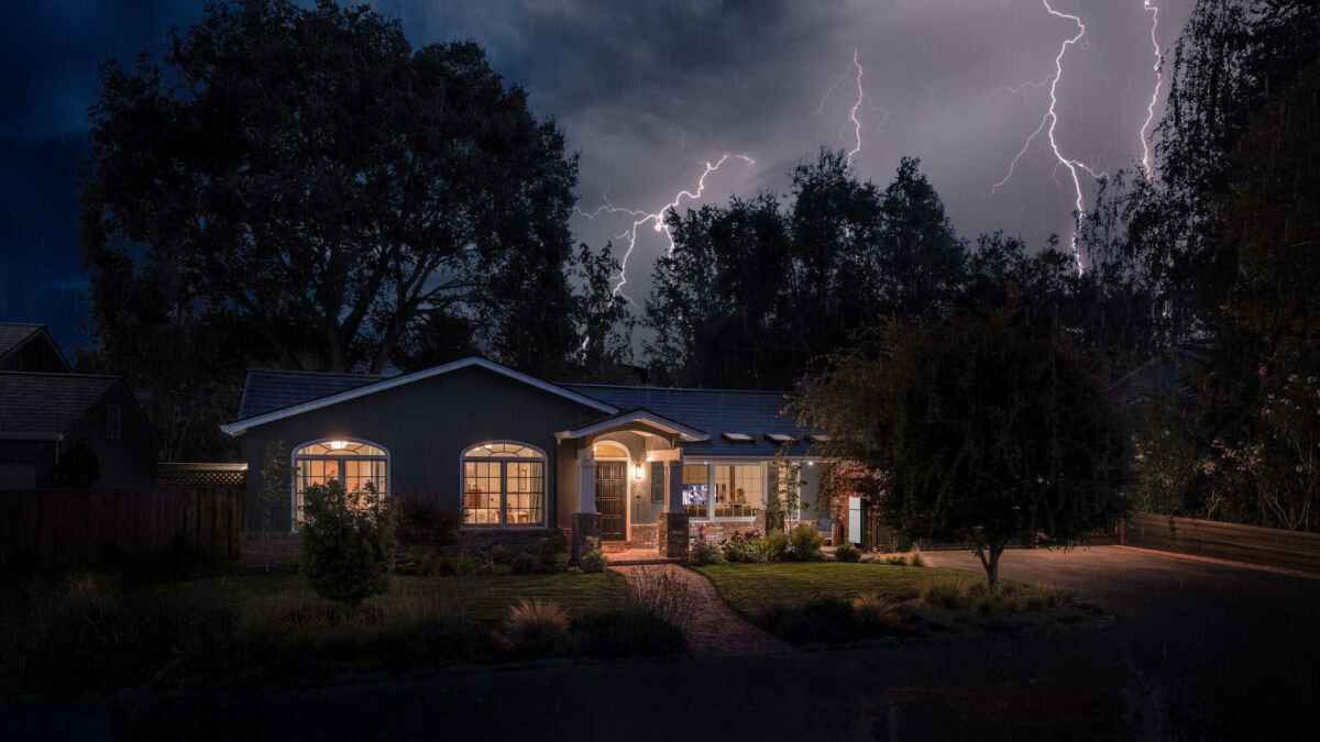 Tesla Solar Roof-powered home illuminated during a nighttime storm in Chatham, NJ, showcasing backup power resilience amid lightning strikes.