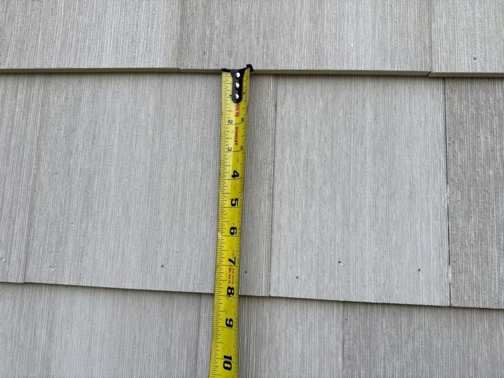 Tape measure showing NuCedar PVC shingle siding installed at 8-inch exposure against manufacturer's 7-inch maximum specification, voiding warranty coverage