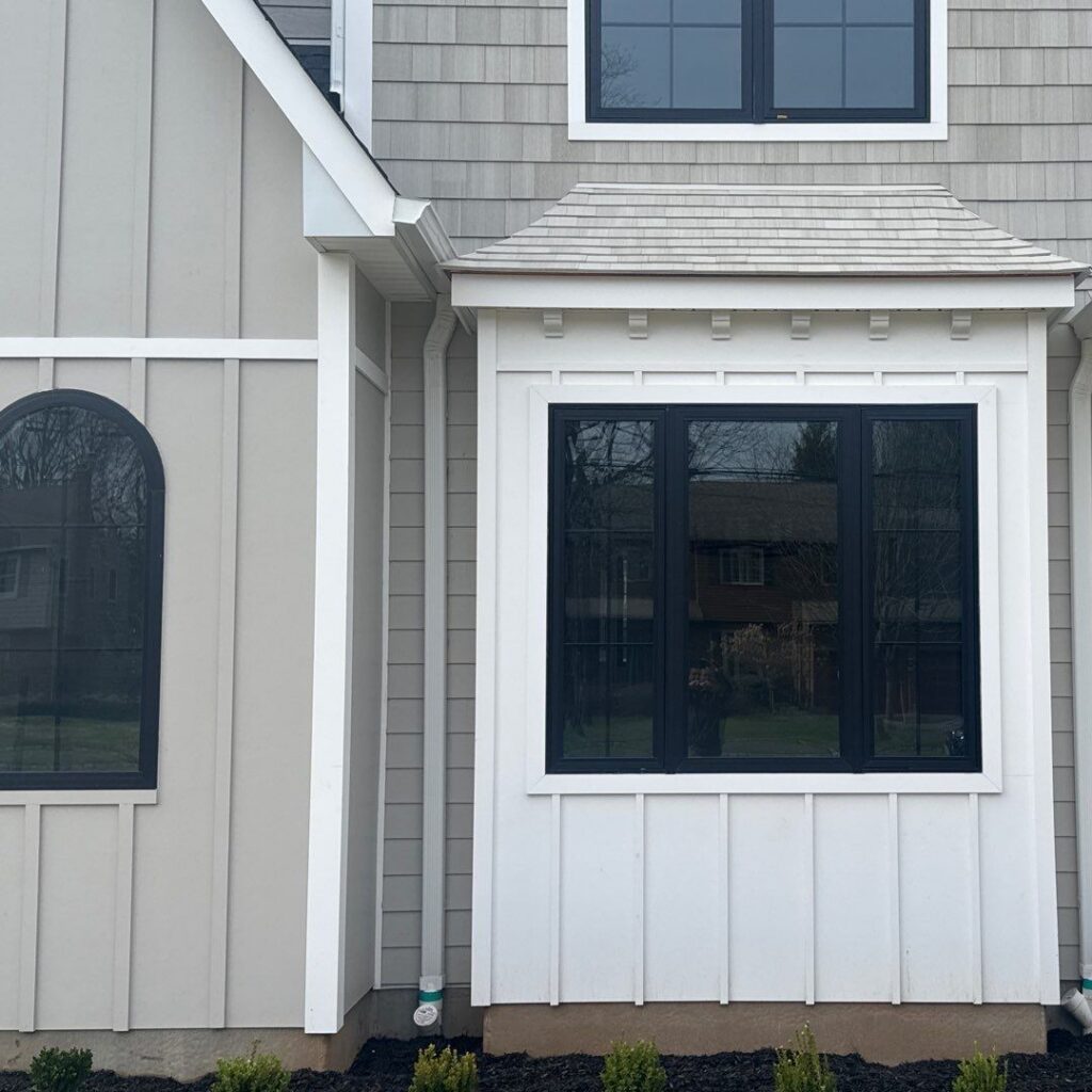 NuCedar PVC siding shingles installed as roofing across a sloped bay window surface on a new construction home, outside the manufacturer's vertical-wall-only specification