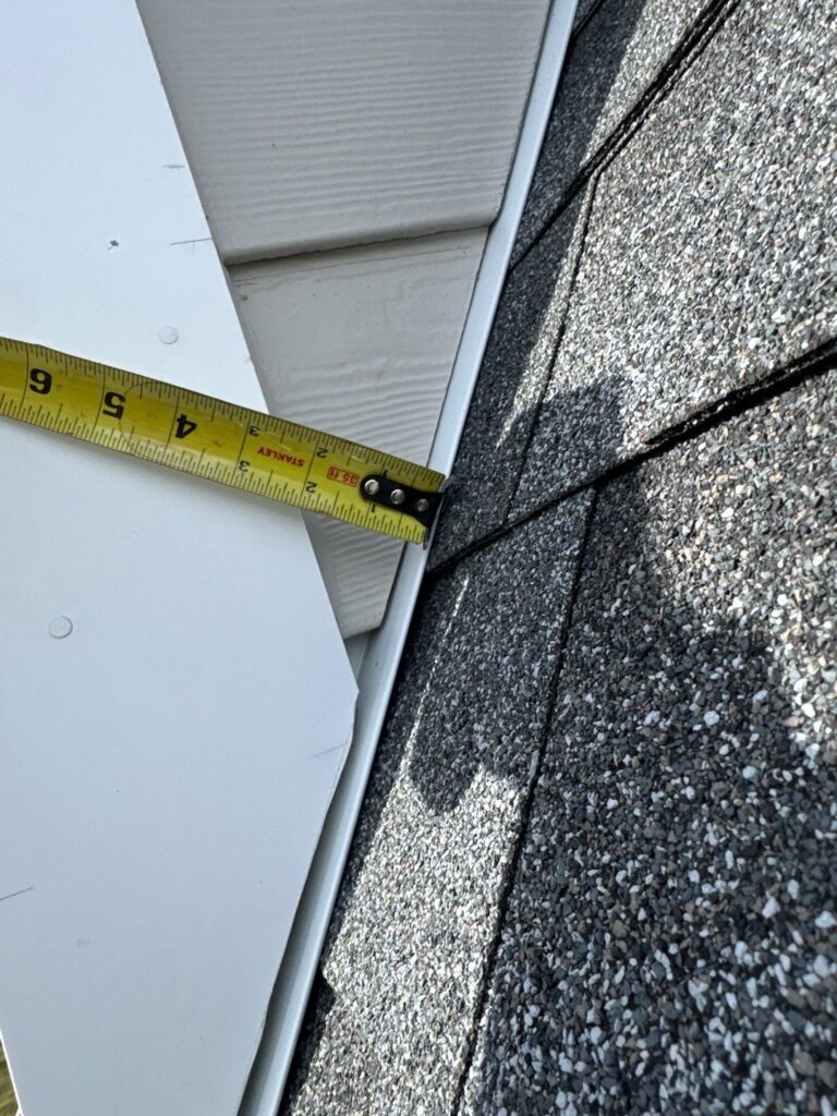 Tape measure showing James Hardie fiber cement siding installed with less than the required 2-inch clearance from an adjacent roof surface