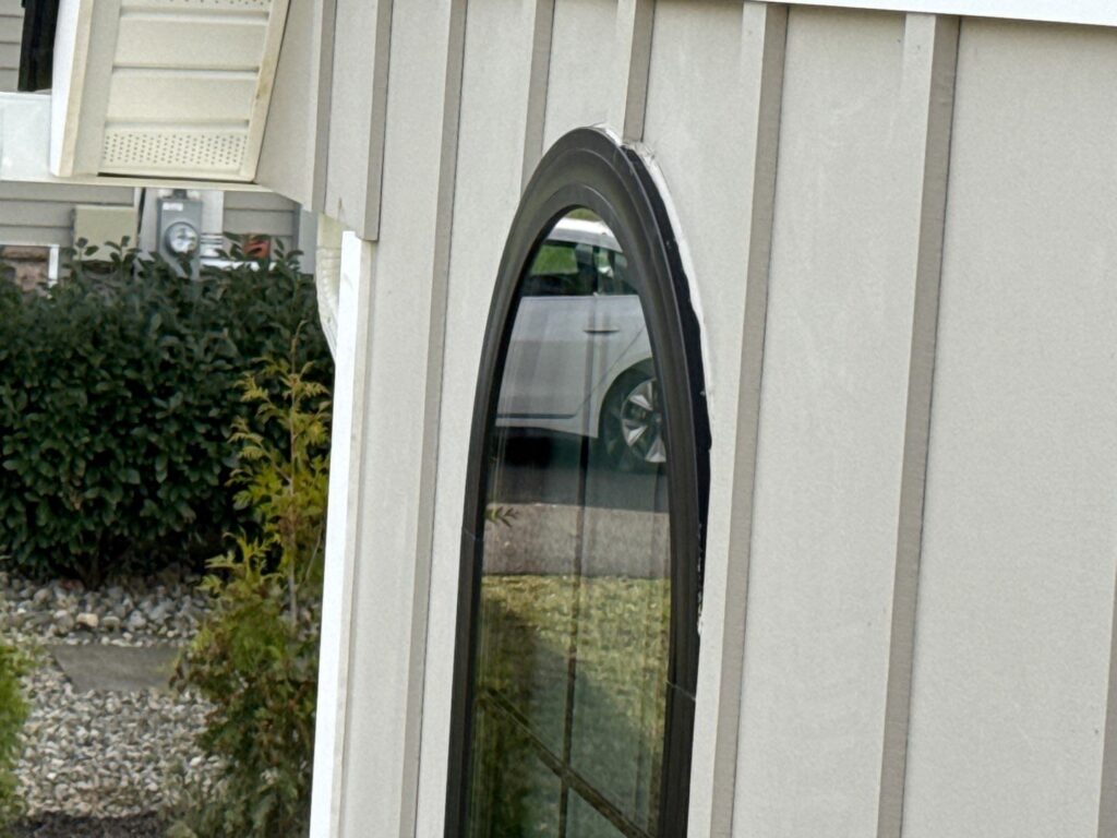 Tall arched radius window on new construction home in Florham Park NJ installed with no head flashing, sealed only with caulk above the curved frame