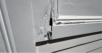 Close-up of deteriorated wood fiber — open void through face of exterior trim board